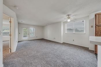 A spacious room with a ceiling fan and carpeted floor